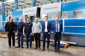 A group of men standing in front of a mpmc machine